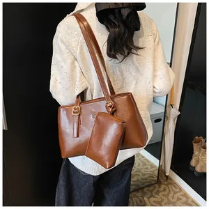 Detail of a brown faux leather tote bag with side metal buckle and matching pouch