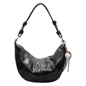Minimalist black crescent shoulder bag with pleated details and baseball keychain