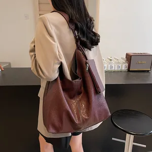 Brown leather tote bag with wide strap and white stitching in a modern interior setting