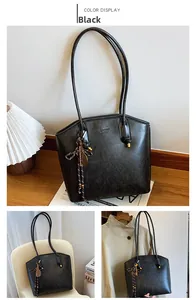 Detail of black leather tote bag with elegant tennis racket charm and thin shoulder strap