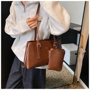 Detail of dark brown faux leather tote bag with gold lettering and small zipper pouch