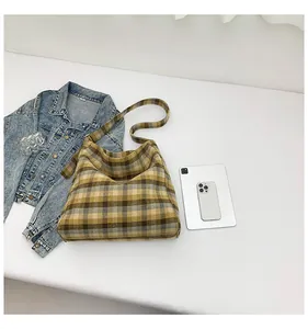 Flat lay of a yellow checkered tote bag with a denim jacket and tablet on white background