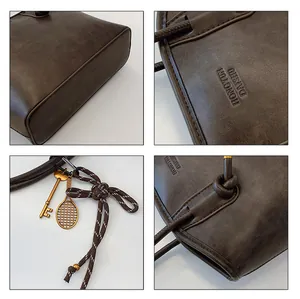 Detail view of vintage dark brown tote bag with leather texture and metal charms