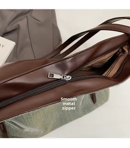 Detailed close-up of smooth silver zipper puller and striped lining on brown bag
