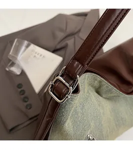 Detail of silver buckles on blue denim and brown leather patchwork shoulder bag
