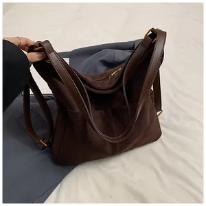 Dettaglio di una grande borsa tote marrone scuro con tessuto strutturato e manici in pelle