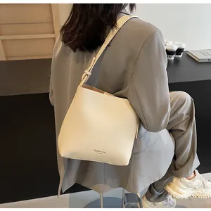 Detail of cream leather bucket bag with gold foil brand text and wide adjustable strap