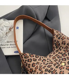 Close-up of leopard print canvas bag featuring brown leather strap and gold chain detail