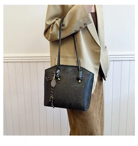 Detail of black leather tote bag with long shoulder straps and tennis racket pendant