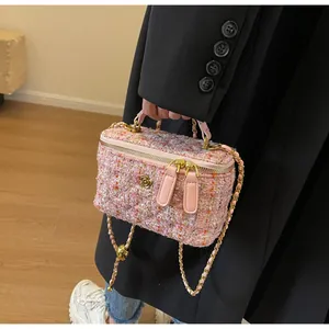 Detail of pink tweed crossbody bag with gold camellia logo and leather chain strap