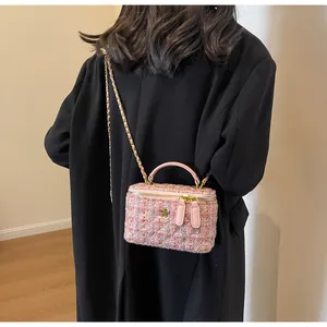 Detail of pink tweed crossbody bag featuring quilted stitching and golden flower ornament
