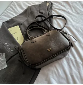 Macro detail of dark brown leather Boston bag with gold metallic logo and side drawstring
