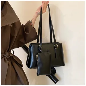 Close-up of matte black leather tote bag with gold hardware and small pouch