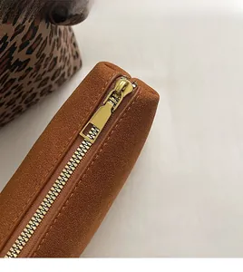 Detail of smooth gold zipper on premium brown suede bag with leopard print accent