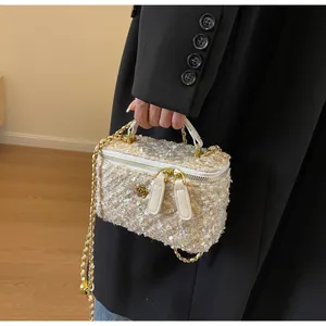 Detail of tweed crossbody bag featuring golden camellia charm and chain strap