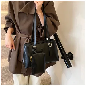 Close-up of black leather tote bag featuring golden hardware and a small hanging pouch