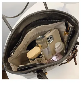 Spacious interior of a dark grey tote bag with beige lining and a zippered pocket