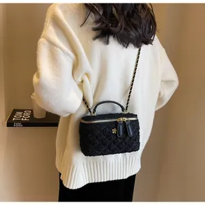Detail of a black tweed mini bag featuring gold hardware and a floral zipper charm