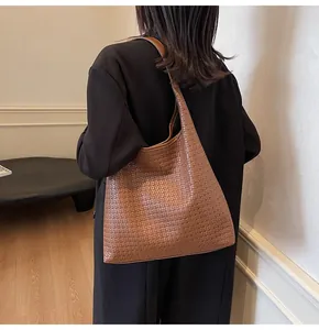 Détail du sac cabas en cuir tressé marron foncé avec large bandoulière sur un mannequin
