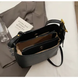 Internal view of black leather bucket bag showing compartments and magnetic snap closure