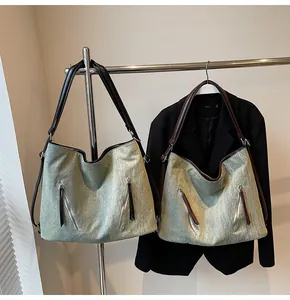 Detail of washed denim tote bag showing metal diagonal zippers and spacious interior design