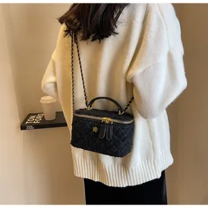 Close-up of black tweed handbag with gold flower charm and elegant chain strap detail