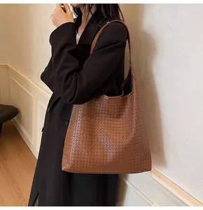 Détails de texture d'un sac hobo tressé marron porté par un mannequin élégant