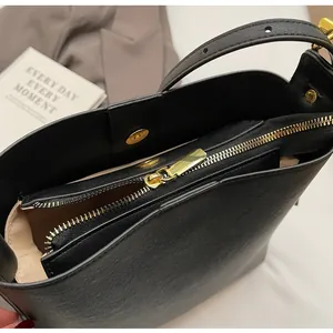 Detail of black leather bucket bag interior with gold magnetic closure and zipper pocket