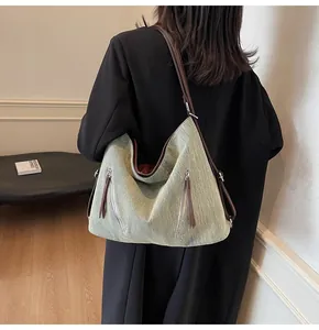 Detail of grey-green tote bag featuring dual vertical zippers and brown leather straps