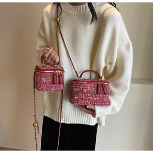 Detail of pink tweed mini bag showing gold flower zipper charm and chain strap