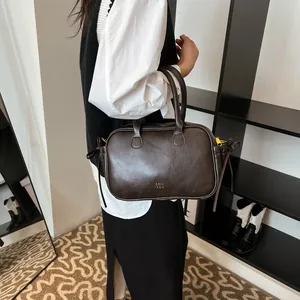 Retro dark brown leather handbag with cylindrical handle and gold brand logo