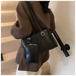 Detailed view of black matte leather tote bag with small pouch worn by a model