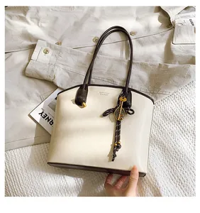 Detailed top view of a cream and brown tote bag featuring a leather texture and metal key charm