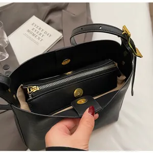 Macro shot of black leather bucket bag interior with a removable zipper pouch and gold clasp