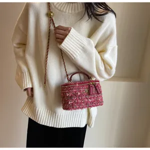 Model wearing a pink tweed handbag with gold camellia detail and chain strap