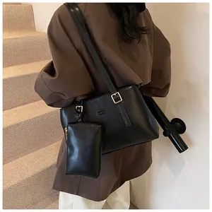 Close-up of black matte leather tote with branded embossing and matching small pouch