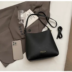 Detail of minimalist black matte leather bucket bag with gold lettering and adjustable strap