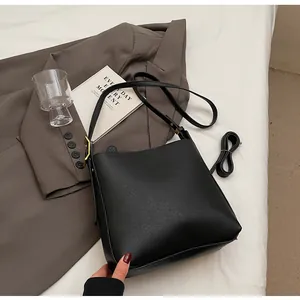 Detail view of black bucket bag with smooth PU leather finish and gold buckle hardware