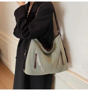 Detailed view of the large grey-green fabric tote with leather trim on a model shoulder