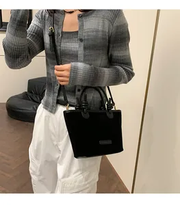 Fashionable black suede tote bag detail showing knot handle and adjustable strap for women