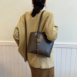 Retro deep brown leather tote bag with tennis racket gold charm on model shoulder