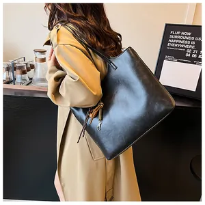 Vista laterale di una grande borsa tote nera vintage abbinata a un trench chic