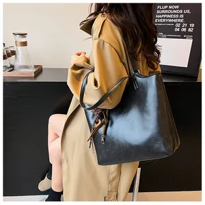 Dettaglio di una borsa tote grande in ecopelle nera con nappe indossata da una modella