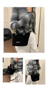Detail of black suede tote bag with dual top handles and adjustable long shoulder strap