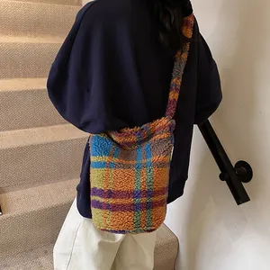 Borsa a secchiello in peluche a quadri multicolore con tracolla larga sulla modella