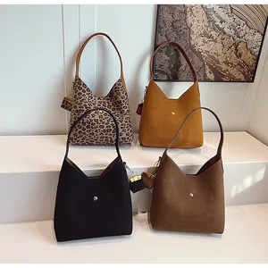 Close-up of stylish leopard print and suede underarm bags with matching mini pouches