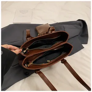 Detailed top view of brown leather tote bag showing triple interior compartments and zipper