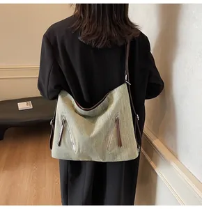 Detail of a large khaki canvas tote bag with brown leather straps shown on a model's shoulder