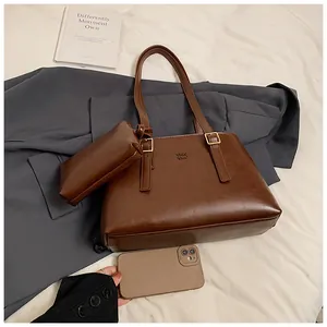 Detail view of brown matte leather tote bag and pouch with golden adjustable buckle