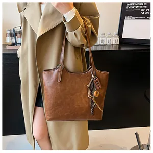 Dettaglio della borsa tote marrone vintage con tracolle regolabili e ciondolo decorativo